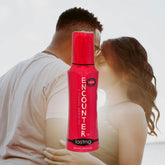 A couple embraces closely, blurred in the background. In the foreground is a bottle of Encounter "Lasting" Silicone Lubricant | 2oz, showcasing its red design. This vegan formulation by Encounter ensures an intimate experience without parabens.